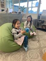 Two children sitting at the bean bags smiling at the camera. 